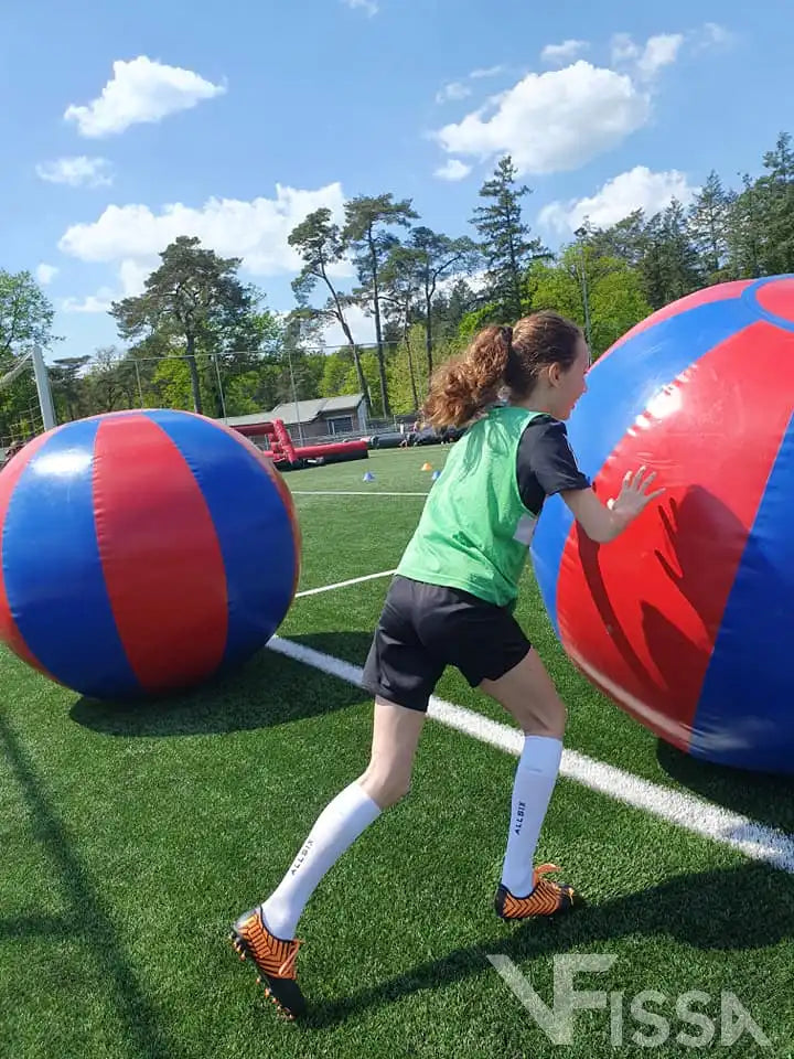 Meisje duwt Big Ball vooruit bij meidenvoetbaldag