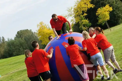 Volwassene klimt op Big Balls en wordt begeleid door medespelers bij Bedrijfsfeest