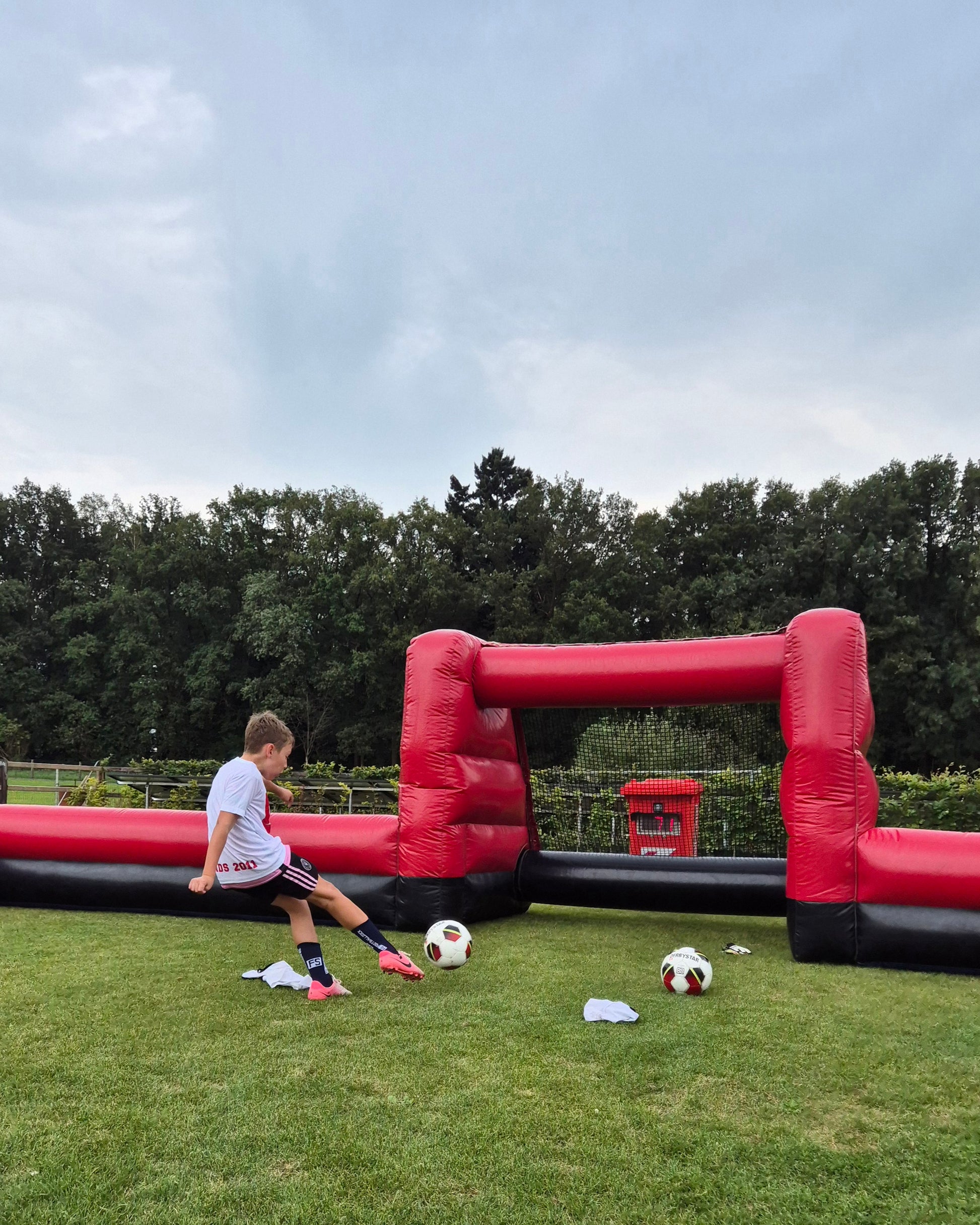 Kinderen schieten op snelheidsmeter bij een voetbalverjaardagsfeest